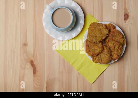 Kartoffelpfannkuchen auf einem Teller und eine Tasse Kaffee Auf einem hölzernen Hintergrund Stockfoto