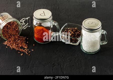 Pfeffer- und Salzglas-Shaker auf schwarzem Beton-Backgroun mit Kopierraum. Stockfoto