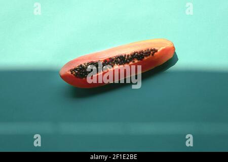 Papaya-Scheibe auf blauem Hintergrund mit Schatten. Trendige Sommerstimmung. Stockfoto