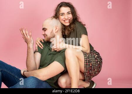 Weißer junger Mann und Frau isoliert auf rosa hält ihn In ihren Händen Stockfoto