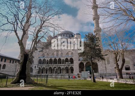 Blaue Moschee (Sultan ahmet) hinter den getrockneten und verwelkten Bäumen mit ihrer herrlichen Ottomanen-Architektur mit blauem Himmel und weißen Wolken. Stockfoto