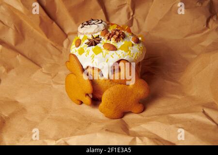 Osterkuchen auf braunem Papier mit Lebkuchen. Handgemachte Panettone mit flüssigen Puderzucker Mandeln, Walnuss und Baiser verziert. Stockfoto