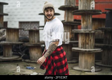 Ein cooler europäischer bärtiger Mann mit Arm-Tattoos lässig gekleidet Rückblickend Stockfoto