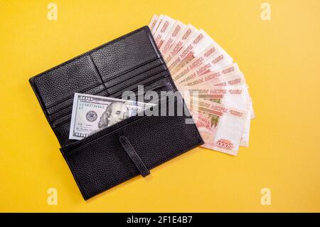 Dollar und Rubel Geld in Brieftasche auf gelbem Hintergrund. Russische Geldscheine von fünftausend Rubel. Stockfoto