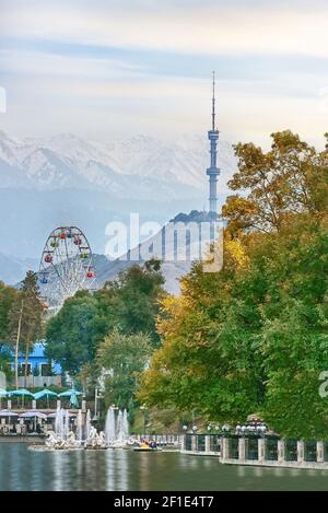 Blick auf den Kok Tobe Turm in Almaty, See und Riesenrad im Gorky Park, Kasachstan Stockfoto