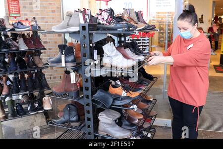 08. März 2021, Mecklenburg-Vorpommern, Rostock: Zur Wiedereröffnung des Einzelhandels im Zentrum der Hansestadt schiebt eine Verkäuferin im Schuhgeschäft Höppner Trolleys mit Schuhen nach draußen. Händler können unter Vorbehalt auf 08.03.2021 in Mecklenburg-Vorpommern landesweit wieder eröffnen. In Rostock und Vorpommern-Rügen ist Einkaufen ohne Voranmeldung möglich, aber in den anderen Regionen des Landes ist dies notwendig. Foto: Bernd Wüstneck/dpa-Zentralbild/dpa Stockfoto