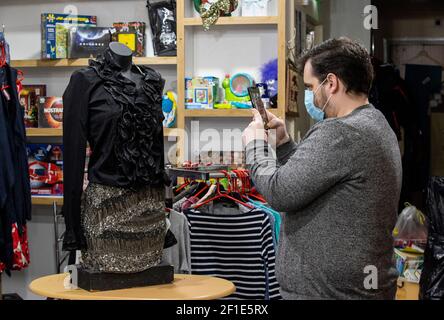 Gerry Keating, Store Manager von Vincent's an der Ormeau Road in Belfast, fotografiert Babyartikel, die auf der Facebook-Seite des Stores veröffentlicht werden. Die Society of St. Vincent De Paul Charity-Shop bietet einen Click and Collect-Service durch Fotografieren von Artikeln im Geschäft mit Kunden anzeigen Artikel über den Shop Facebook-Seite, und in der Lage, Kontakt und kaufen Artikel für die spätere Sammlung. Stockfoto