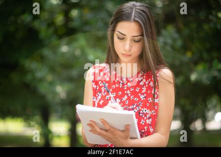 Portrait einer weiblichen Kursteilnehmer studieren in einem Park vor der Schule Stockfoto