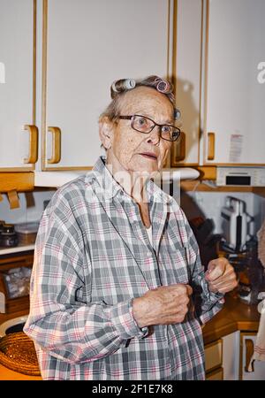 Ältere schwedische Frau in Haarwickler in der Küche. Konzept des Lebensstils Stockfoto