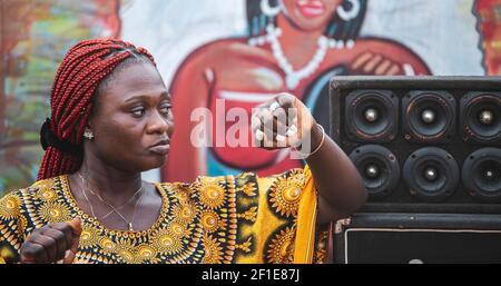 Afrikanische Frau, die in der Nähe von Sprechern an einem Strand in Accra steht Ghana Stockfoto