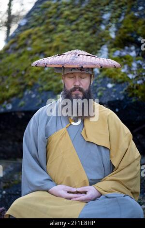 Europäischer Mann mit Bart meditiert in traditionellem, japanischem Shugendo-Outfit im Freien Stockfoto