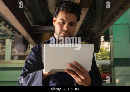 Porträt des Mechanikers, der mit seinem digitalen Tablet arbeitet automatische Reparatur Stockfoto