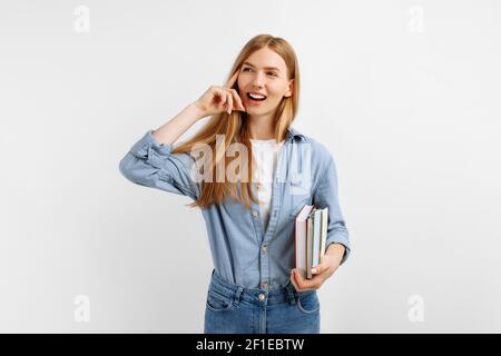 Portrait von glücklicher nachdenklicher junger Frau, die Bücher hält und schaut Beim Kopieren wird der Platz auf weißem Hintergrund isoliert Stockfoto