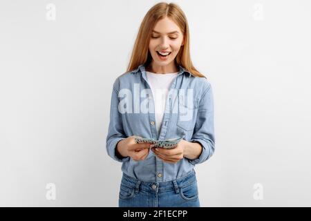 Glückliche junge zielgerichtete Frau, die Geld über isolierten weißen Hintergrund, Wirtschaftskonzept, Geldverteilung zählt Stockfoto