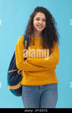 EIN TEENAGER-MÄDCHEN MIT LOCKIGEN HAAREN STEHEND MIT GEFALTETEN ARMEN Stockfoto