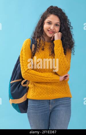 PORTRÄT EINES TEENAGERS, DER MIT EINER TASCHE STEHT UND GLÜCKLICH ANSCHAUT KAMERA Stockfoto