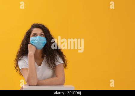 EIN TEENAGER TRÄGT GESICHTSMASKE SITZEND UND DENKEND Stockfoto