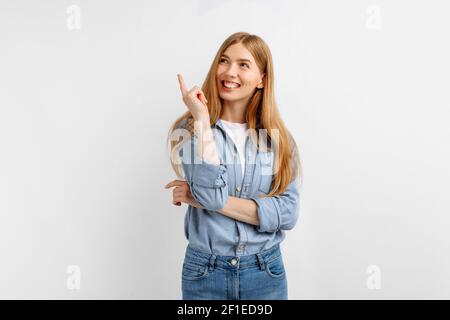 Aufgeregt glücklich junge Frau zeigt Finger nach oben in den Kopierraum Während Sie isoliert auf weißem Hintergrund stehen Stockfoto