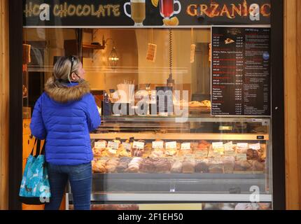 Krakau. Krakau. Polen. Frau, die vor dem Fenster von Takeway und Lieferung von Lebensmitteln, Süßwaren und Café. Stockfoto