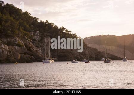 Boote bei Sonnenuntergang in der kleinen Bucht von Cala Benirras, Ibiza-Insel. Stockfoto
