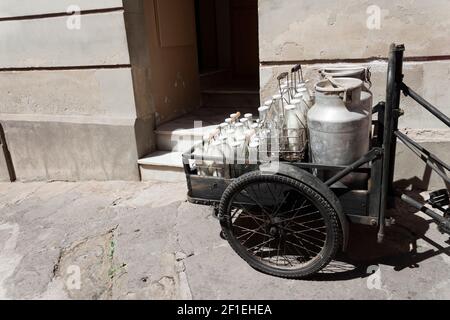 Flaschen und Aluminiumdosen Milch für die Lieferung in vintage rostigen Milchmann Fahrrad. Stockfoto