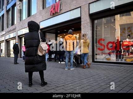 Leipzig, Deutschland. März 2021, 08th. Kunden stehen vor dem Eingang eines H&M-Stores in der Petersstraße. Nach einer einwöchigen Corona-induzierten Lockdown bieten viele Händler mit "Click & Meet" ein neues Konzept an, das ab sofort das Einkaufen mit einem Termin ermöglicht. Quelle: Hendrik Schmidt/dpa-Zentralbild/ZB/dpa/Alamy Live News Stockfoto