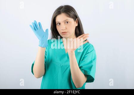 Ärztin in medizinischen Handschuhen, die Hände auf weißem Hintergrund zeigen Stockfoto