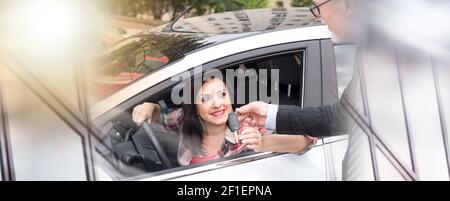 Autoverkäufer, der hübsche junge Frau Autoschlüssel gibt; Mehrfachbelichtung Stockfoto