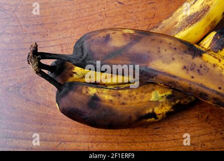 Alte geschwärzte Bananen auf Holztischplatte, norfolk, england Stockfoto