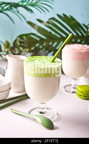 Dalgona Matcha und Erdbeer Latte, cremig geschlagener Matcha Grüner Tee und Erdbeere mit Pflanze auf dem Hintergrund. Stockfoto