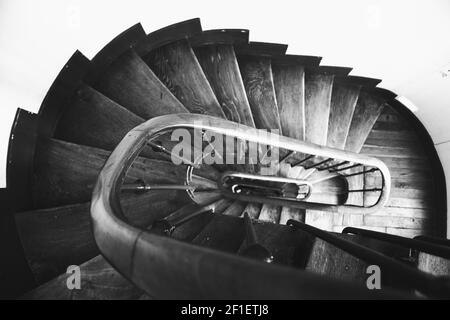 Typische schmale Wendeltreppe mit Geländer im alten Pariser Haus. Selektiver Fokus. Schwarzweißfoto Stockfoto