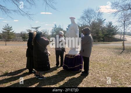 Am Ende eines Gottesdienstes im Freien beten Gläubige aus dem Weltapostolat des hl. Michael zu einer Statue der Jungfrau Maria. In einem Park in Queens, N Stockfoto