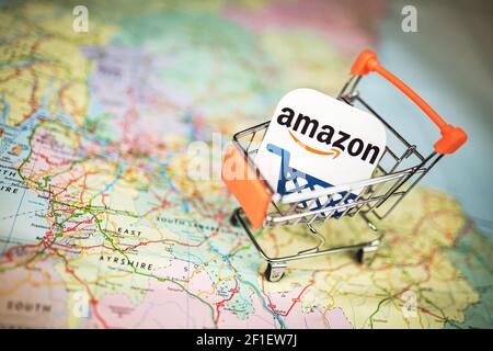 Amazon-Logo in einem kleinen Einkaufswagen über der UK-Karte. Online-Shopping, Amazon-Einkauf, E-Commerce-Konzept Stockfoto