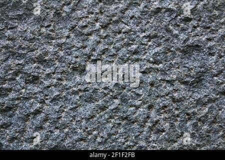 Hintergrund, Textur - die Oberfläche eines bewusst rauhen behauenen Granitblocks Stockfoto