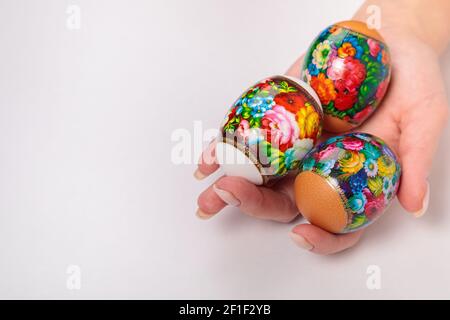 Ostern. Chokhloma Eier in den Händen eines Mädchens, auf einem hellen Hintergrund. Für Text platzieren. Eieraufkleber Stockfoto