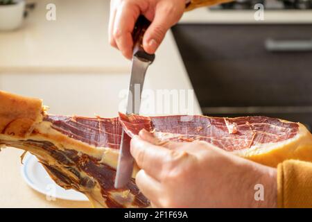 Detail von Schinken laufen von Menschenhand in der Küche zu Hause gemacht. Super Essen. Köstliche Vorspeise. Gourmet-Food-Konzept Stockfoto