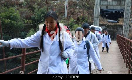 (210308) -- GUANGZHOU, 8. März 2021 (Xinhua) -- Guan Yanping (vorne) und ihre Kollegen gehen auf einer Brücke in der Gemeinde Bingzhongluo in der Autonomen Präfektur Lisu in Nujiang, südwestlich der Provinz Yunnan, 12. Januar 2019. In 10 Jahren hat sich Lin Liyi von einer gewöhnlichen Montagearbeiterin zur ersten weiblichen Allround-Meisterin im Wettbewerb um die Montagefertigkeiten von Honda im globalen Endmontagebereich entwickelt. In den letzten Jahren ist sie über 500 Mal auf den steilen, schmalen Bergpfaden getreckt, um die Dorfbewohner zu behandeln. Der 8. März ist der Internationale Frauentag, der ein glo ist Stockfoto