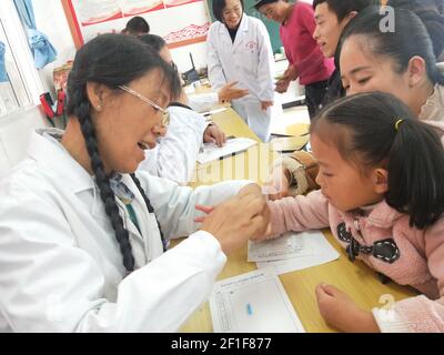 (210308) -- GUANGZHOU, 8. März 2021 (Xinhua) -- Guan Yanping (L) bietet kostenlose medizinische Versorgung für ein Kind im Bezirk Gongshan in der Autonomen Präfektur Lisu in Nujiang, südwestlich der Provinz Yunnan in China, 25. Oktober 2019. Im Jahr 2017 verließ Guan Yanping Zhuhai aus der südchinesischen Provinz Guangdong, um als Hilfe-Arzt in Nujiang in der südwestlichen Provinz Yunnan zu arbeiten. In den letzten Jahren ist sie über 500 Mal auf den steilen, schmalen Bergpfaden getreckt, um die Dorfbewohner zu behandeln. Der 8. März ist der Internationale Frauentag, der ein globaler Tag ist, an dem soziale, wirtschaftliche, kulturelle und Stockfoto