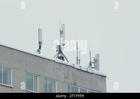 Mobilfunkantenne der Basisstation auf einem auf dem Dach eines Wohnhauses gegen einen grauen Himmel. 3g, 4g, 5g. Stock Foto mit leerem Platz für Text und Design. Stockfoto