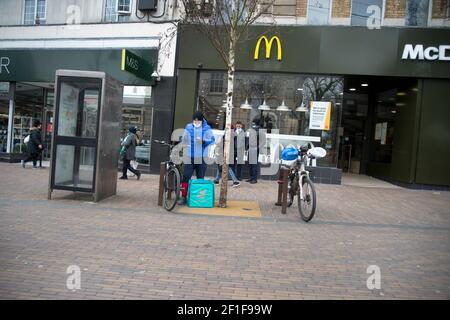 London, Hackney, Großbritannien. Deliveroo Radfahrer warten auf die Lieferung von McDonalds. Stockfoto