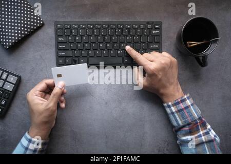 Draufsicht auf Mann Hände halten Kreditkarte und tippen Auf der Tastatur Stockfoto