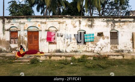 Murshidabad, Westbengalen, Indien - Januar 2018: Vor den schmuddeligen Mauern eines alten Hauses in der Stadt Murshidabad hingen Kleider zum Trocknen auf. Stockfoto