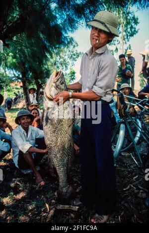 Ein Fischer mit einem großen Fisch hat er gefangen, Küstendorf, Nord-Vietnam, Juni 1980 Stockfoto