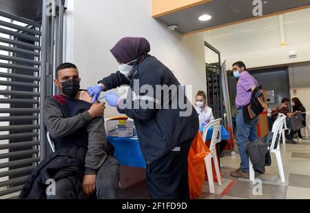 Lamed Hei Checkpoint, Palästina, 8th. März 2021. Ein Sanitäter der israelischen Agentur für den Notfall "Magen David Adam" impft am Montag, den 8. März 2021, einen palästinensischen Arbeiter mit der ersten Dosis des Impfstoffes "Moderna COVID-19" am Checkpoint Lamed Hei zwischen Gusch Etzion und Beit Shemesh ein. Israel startete eine zweiwöchige Kampagne, um etwa 100.000 palästinensische Arbeiter aus dem Westjordanland zu impfen, die Arbeitsgenehmigungen in Israel und jüdischen Siedlungen besitzen. Kredit: UPI/Alamy Live Nachrichten Stockfoto