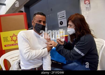 Lamed Hei Checkpoint, Palästina, 8th. März 2021. Ein Sanitäter der israelischen Agentur für den Notfall "Magen David Adam" impft am Montag, den 8. März 2021, einen palästinensischen Arbeiter mit der ersten Dosis des Impfstoffes "Moderna COVID-19" am Checkpoint Lamed Hei zwischen Gusch Etzion und Beit Shemesh ein. Israel startete eine zweiwöchige Kampagne, um etwa 100.000 palästinensische Arbeiter aus dem Westjordanland zu impfen, die Arbeitsgenehmigungen in Israel und jüdischen Siedlungen besitzen. Kredit: UPI/Alamy Live Nachrichten Stockfoto