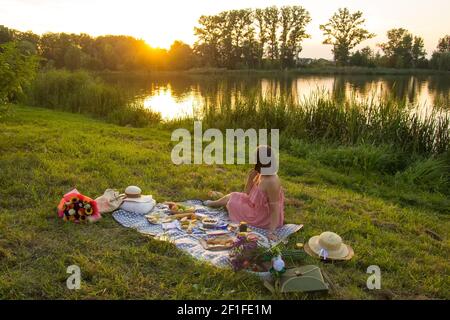 Eine junge Frau sitzt auf einem Picknick in einem Park Am Ufer eines Flusses Stockfoto