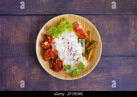 Hausgemachtes japanisches gegrilltes Hähnchengericht mit Gemüse und Reis, serviert auf einer Bambusplatte. Rustikale Holztisch Hintergrund. Stockfoto