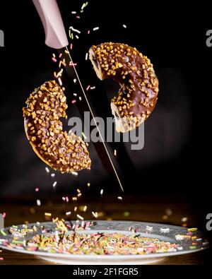 Halb geschnittener Donut mit Messer in der Luft Stockfoto