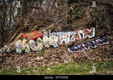 Weggeworfene Blumen-Tribute bei der Beerdigung auf dem Friedhof auf Müll Pile Mama Gran und Papa Blumen für das Recycling nach der Beerdigung Auf dem Friedhof Stockfoto