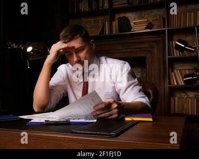Müde Angestellte oder Geschäftsmann arbeitet mit Dokumenten spät in der Nacht. Stockfoto
